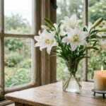 Weiße Blumen auf einem Tisch neben einer brennenden Kerze
