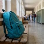Schulrucksack für Mädchen lehnt an einer Bank im Schulflur
