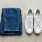 Locker geschnittene Jeans und Sneaker vor hellem Hintergrund