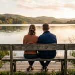 Paar sitzt nebeneinander auf einer Bank am Wasser