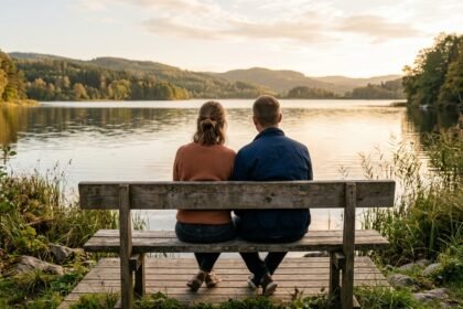 Paar sitzt nebeneinander auf einer Bank am Wasser