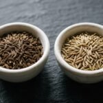 Kümmel und Kreuzkümmel: zwei Schälchen mit Kümmelsamen und Kreuzkümmelsamen nebeneinander