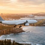 Wie lange fliegt man nach Australien: Flugzeug über der Küste von Sydney bei Sonnenaufgang