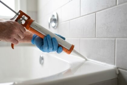 Silikonfugen werden mit der Kartuschenpistole zwischen Wanne und Fliesen gezogen