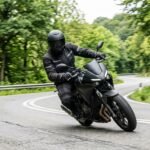 Motorradfahrer auf einer Landstraße in Schräglage, Schutzkleidung und Helm