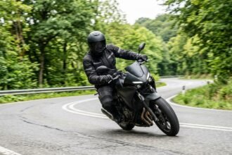 Motorradfahrer auf einer Landstraße in Schräglage, Schutzkleidung und Helm