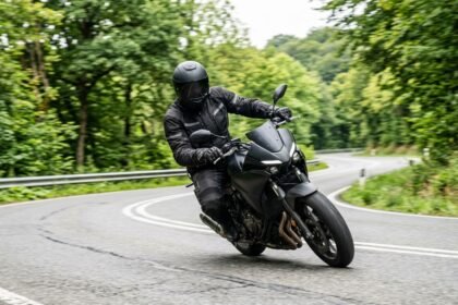 Motorradfahrer auf einer Landstraße in Schräglage, Schutzkleidung und Helm