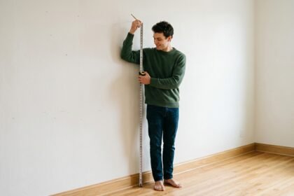 Junger Mann misst seine Körpergröße an einer Wand